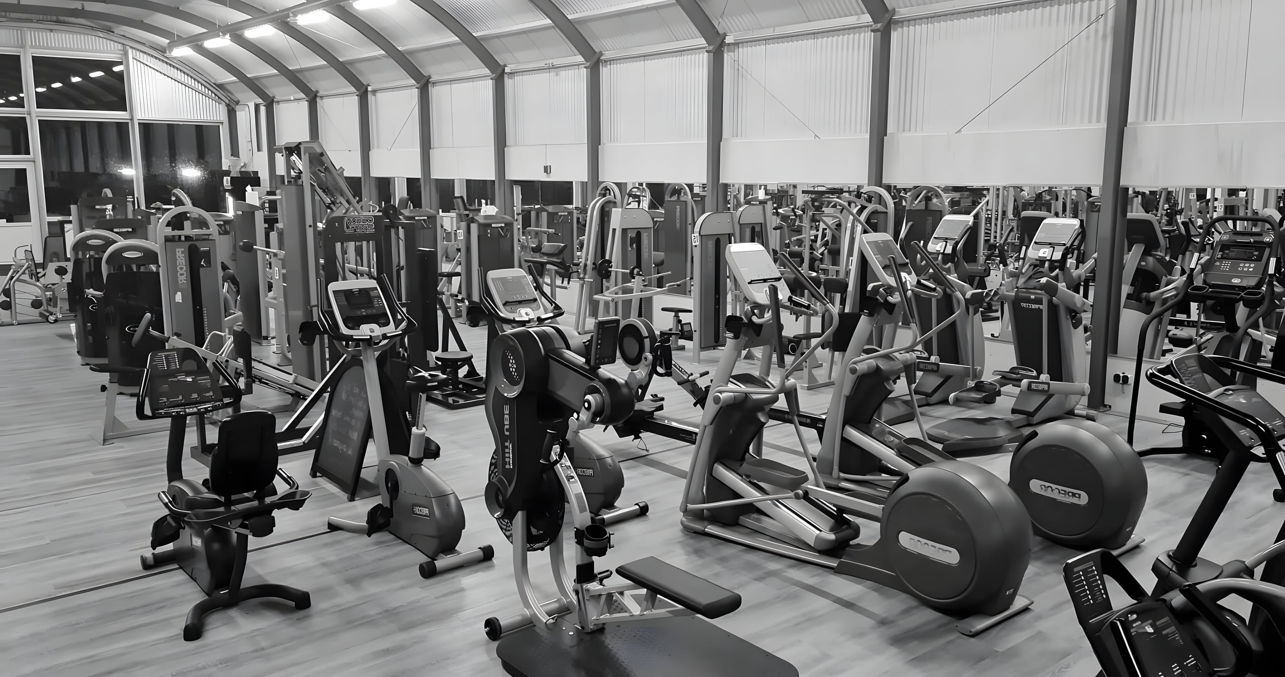 De fitnessvloer van Bodysupport Groningen met rijen cardio- en krachtapparatuur onder een hoge hal